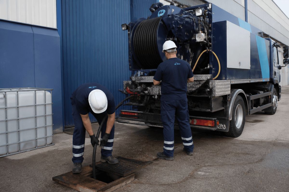Equipo de desatascos trabajando junto a una arqueta en el exterior de una nave industrial